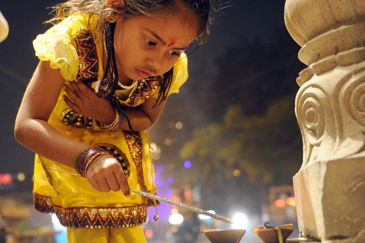 A festively dressed Indian girl lights a sparkler at a the temple for the Hindu Divali festival in Jaipur, India, 13 November 2012. The entire city is decorated, lit up and fireworks are set-off during the five-day festival of lights. Photo: Jens Kalaene/