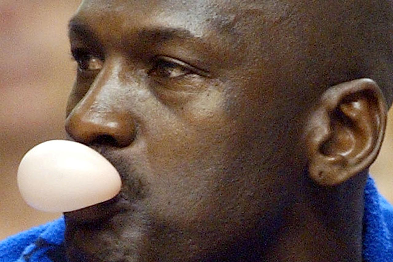 FILE PHOTO: Washington Wizards' Michael Jordan blows a bubble while sitting on the bench during a National Basketball Association game against the Philadelphia 76ers