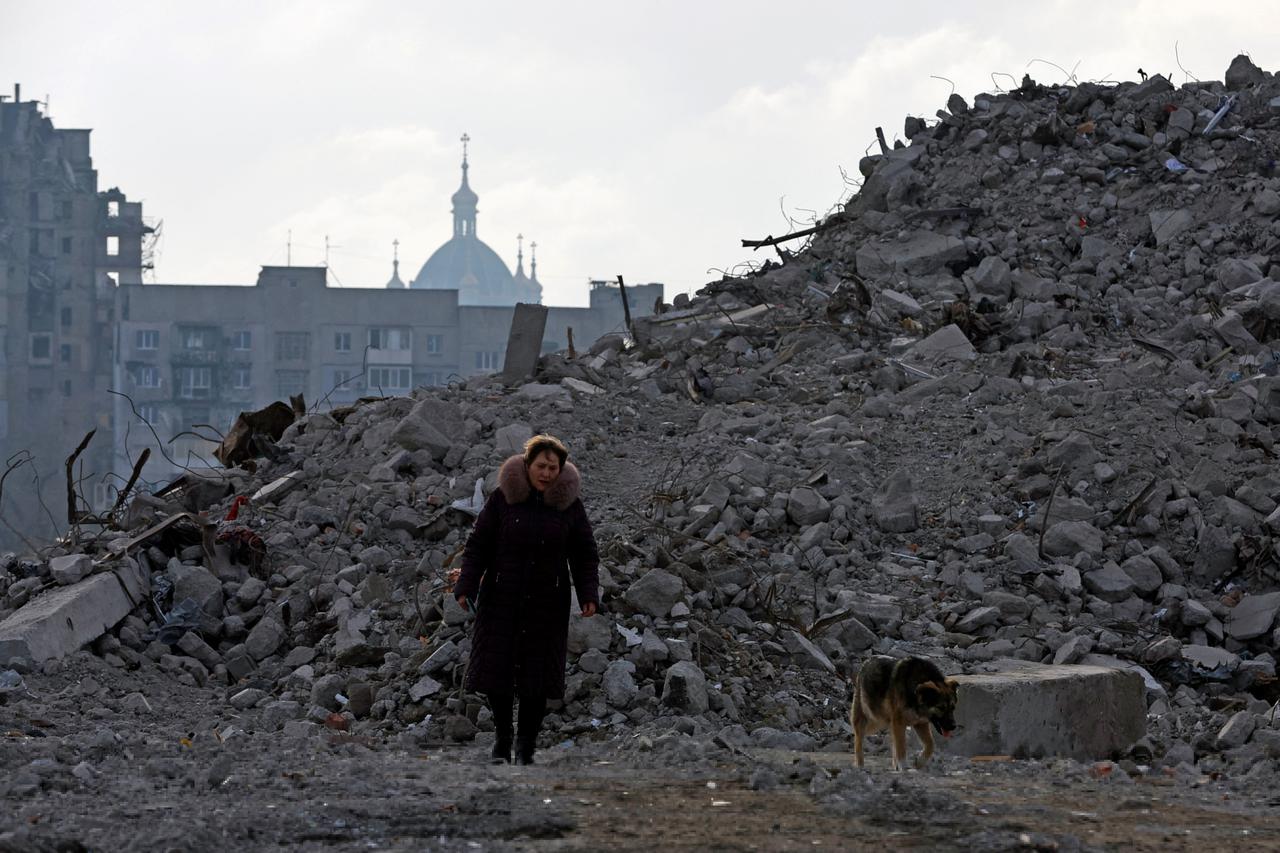 Tatiana Bushlanova walks next to the ruins of her apartment block, demolished due to heavy damage, in Mariupol