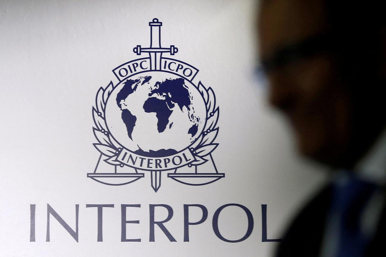 FILE PHOTO: A man passes an Interpol logo during the handing over ceremony of the new premises for Interpol's Global Complex for Innovation in Singapore