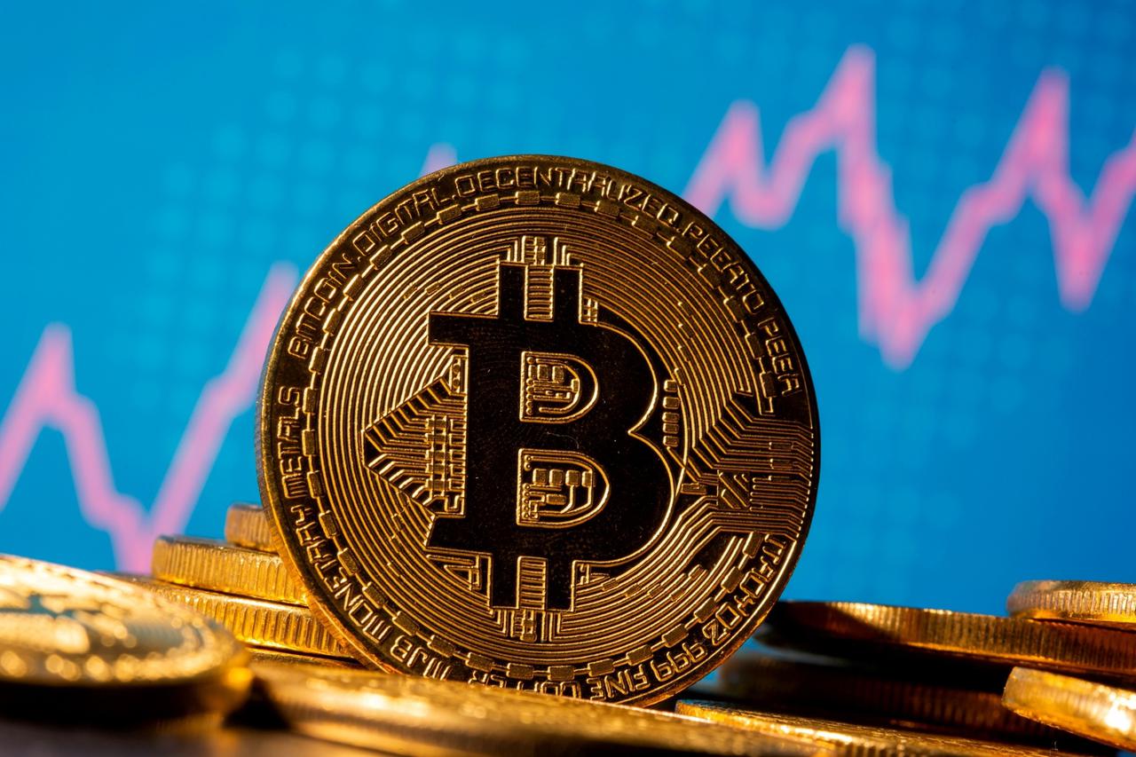 FILE PHOTO: A representation of virtual currency Bitcoin is seen in front of a stock graph